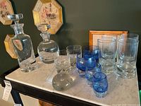 Group shot showing both decanters, clear and blue glasses, paperweight