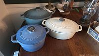 Group view of three Dutch ovens showing colors, shapes, lids and embossed branding