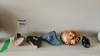 Five items side by side: fossil, two mineral plaques, wood carving, ceramic bird