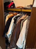 Closet view showing multiple women’s jackets, shirts on hangers