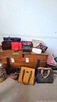 Wide shot of all handbags arranged on and in front of wooden chest