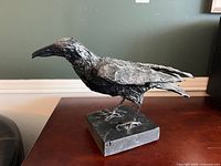 Side view of crow sculpture on base