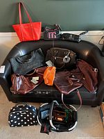 All purses arranged on couch with shoe polish kit and gloves visible