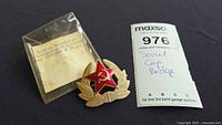 Badge beside original plastic packet and auction tag