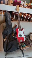 Bass guitar with gig bag, strap and accessories on couch