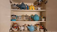 Cabinet view showing all teapots, coffee makers, cups and serveware
