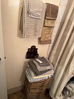 Overview of hanging towels, folded towels on woven storage tower, wall plaque
