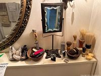 Overall lot on vanity including mirror, lighters, knives, baby shoes and brushes