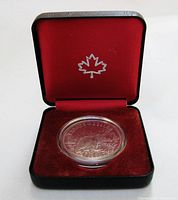 Coin displayed in open red-lined clamshell box