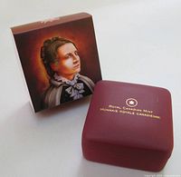 Outer art box beside closed maroon Royal Canadian Mint clamshell case