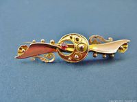 Front view showing gold bar brooch design, faux ruby and decorative details