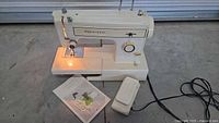 Front view of Kenmore 1211 sewing machine with manual and foot pedal