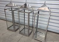 Front angle view of three silver metal and glass lanterns
