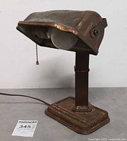 Front view of lamp showing full structure, rust patina, pull chain and bulb