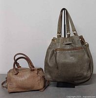 Brown textured Roots handbag and gray drawstring Roots handbag side by side front view