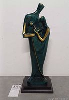 Front view of green patinated bronze parent and child sculpture on black base