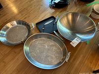 Group shot showing All-Clad wok, roaster pan, perforated pan, square cast iron grill pan and press