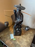 Full front view of carved wooden fisherman statue on tabletop
