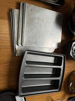 Stack of aluminum baking sheets with three-section pan on top