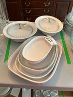 Overall view of lot showing two round casseroles with lids and stack of oval and rectangular bakers