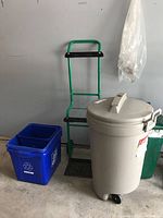 Hand truck, garbage can with lid, recycle bin visible together