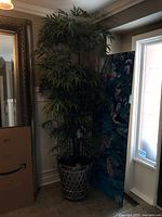 Full view of faux bamboo tree in metal pot placed in corner