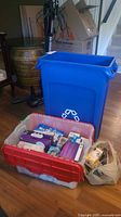 Blue recycling bin, red/clear storage tote filled with packaged bulbs and bag of bulbs