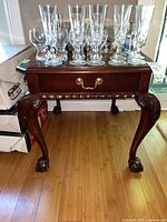 Front view showing tabletop, drawer with brass pull, carved legs and claw feet