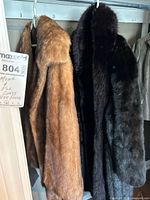 Two mink coats hanging, dark full-length and light fingertip-length