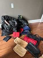 Group of assorted purses and wallets with additional bags in garbage bags
