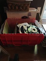 Plastic tote with stack of 45 RPM records and boxed USB turntable in background