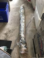 Entire rolled tapestry wrapped in plastic lying on floor