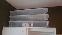Three stacked clear Bella under-bed totes on cabinet
