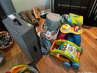 Lot overview showing push walker, ride-on activity toy, storage bin of books, foam playmat squares