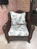 Front view of brown wicker armchair with cushions