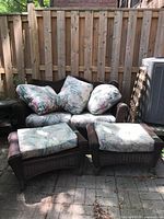 loveseat with two ottomans and cushions on patio