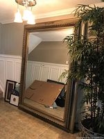 Full view of extra-large ornate mirror leaning against wall