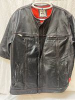 Full front view of vest showing perforated leather, zipper pockets, snaps, red lining