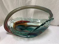 Side view of multicolor art glass basket showing clear handle and swirl colors