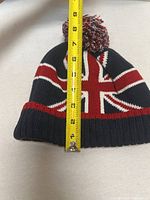 Front of beanie with tape measure showing height to pom ~9 in