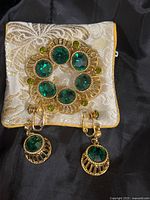 Brooch and earrings on cream brocade pouch