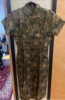 Full front view of green brocade cheongsam dress on hanger