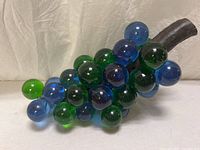 Full view of blue and green glass grape cluster showing marbles and faux wood stem