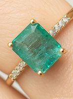 Close-up of emerald and diamond accented band on finger