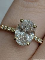 Ring on finger showing oval lab diamond and accent diamonds