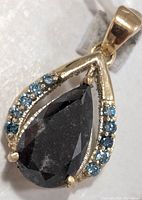 Front view of 10K gold pendant showing black diamond and blue lab diamond accents