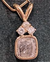 Front view of gold pendant showing cushion diamond and two round diamonds