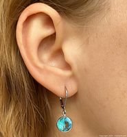 Earring worn on ear showing size, drop style, blue gemstone