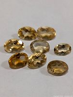 Eight oval yellow faceted gemstones on white background