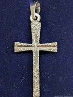 Front view of silver cross pendant showing textured surface and bail